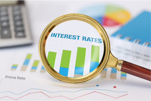 A gold magnifying glass zooms in on a bar chart and the words Interest Rates