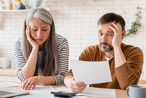 Parents examine paperwork and look concerned about mistakes in their student loan borrowing.
